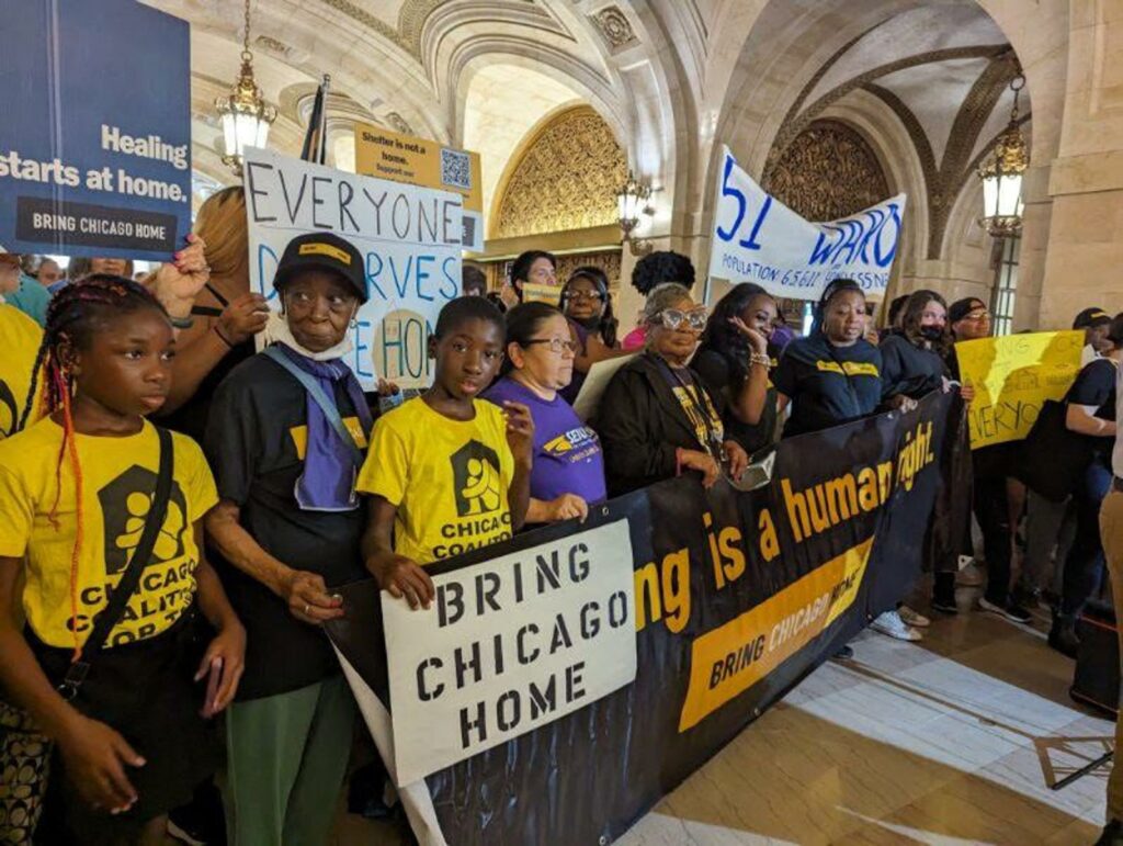 Los partidarios de Bring Chicago Home se concentran con pancartas y carteles en el interior del Ayuntamiento.