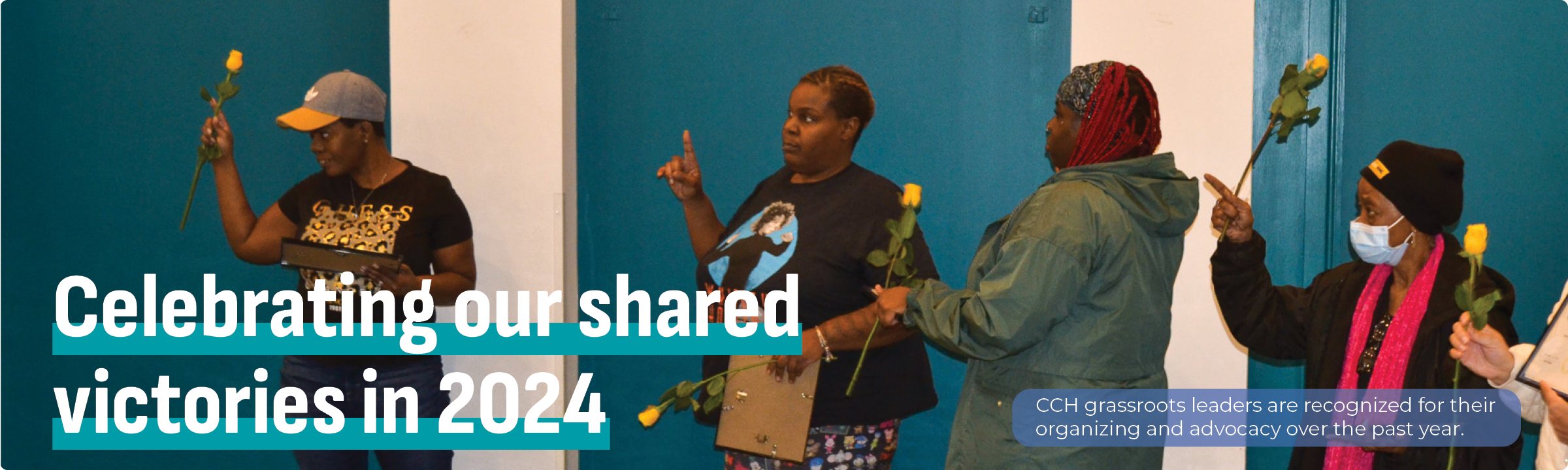 CCH grassroots leaders stand in front of a room holding up yellow roses.