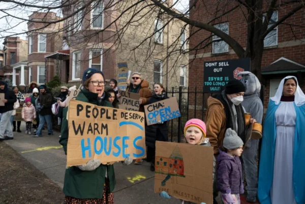 Group of people March holding signs that say, "People deserve warm houses" and "CHA" Open the doors".