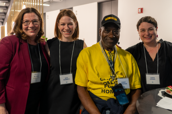 4 people pose for the camera. One is wearing a bright yellow shirt.