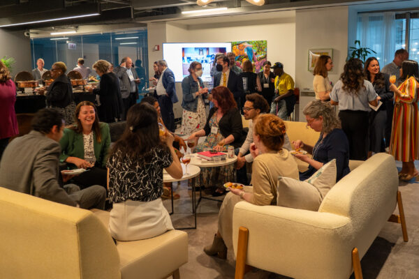 A room full of people, some standing and some sitting, in conversation.