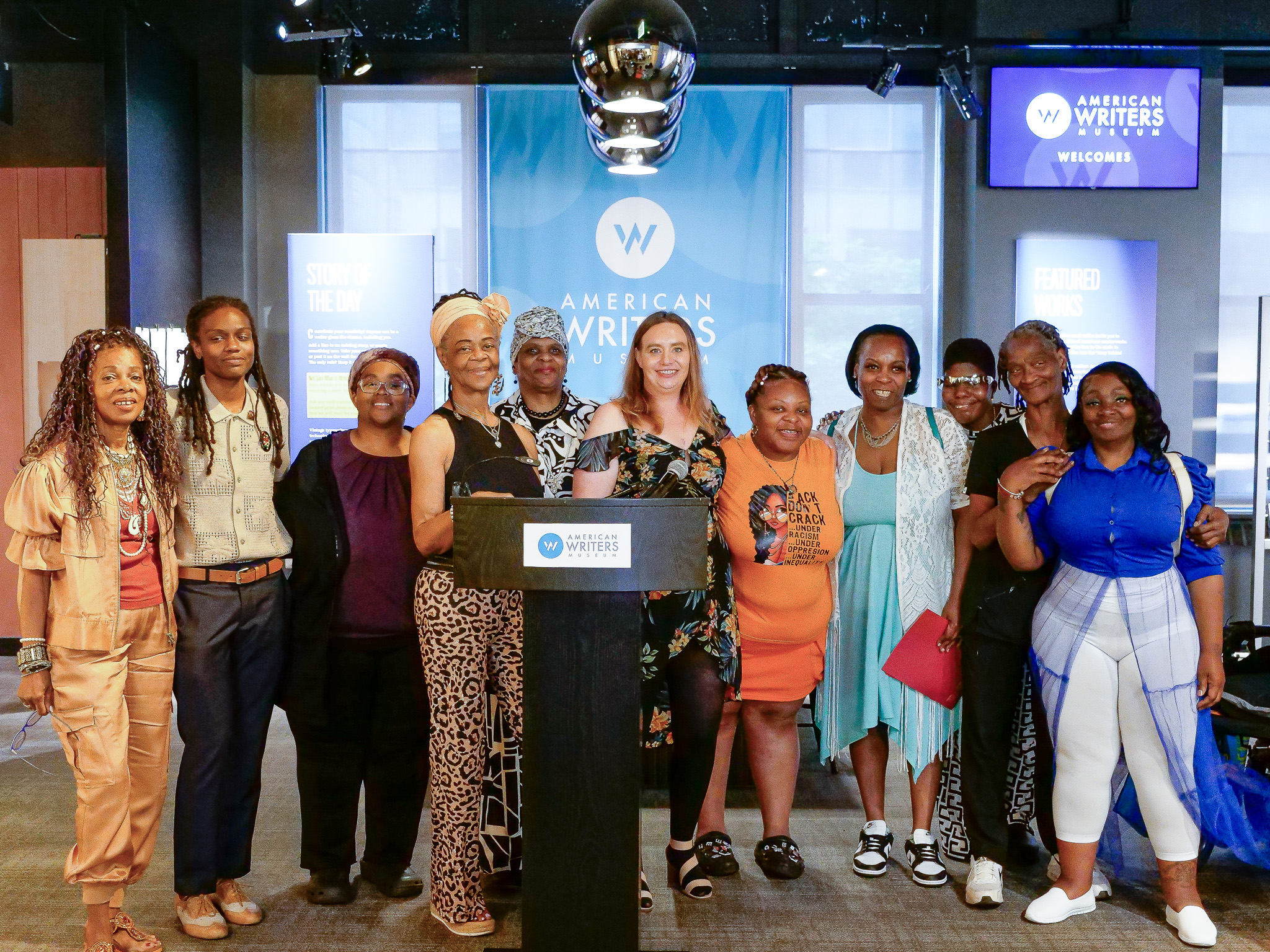 A group of people stand behind a podium with a microphone.