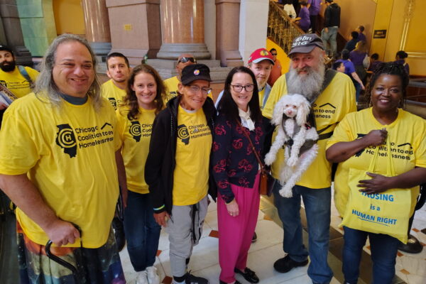 A group of people in bright yellow Chicago Coalition to end Homelessness shirts smile to the camera.