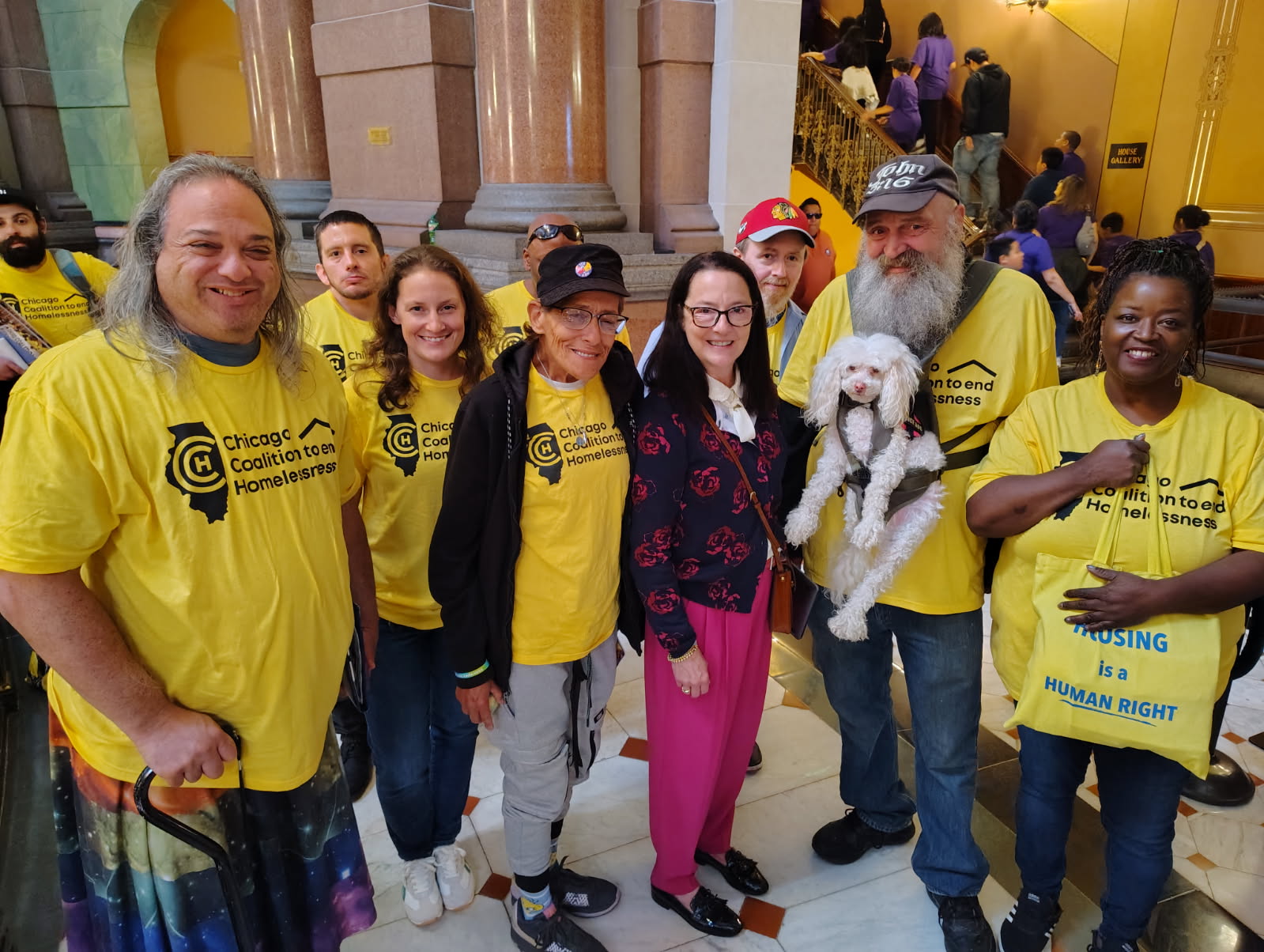 A group of people in bright yellow Chicago Coalition to end Homelessness shirts smile to the camera.