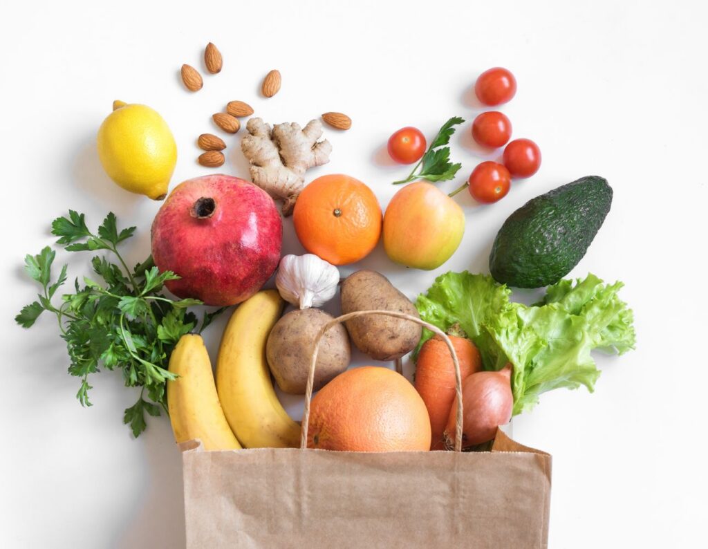 Grocery bag with various fruits, vegetables, and nuts coming out the top.