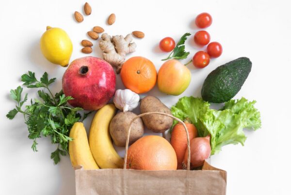 Grocery bag with various fruits, vegetables, and nuts coming out the top.